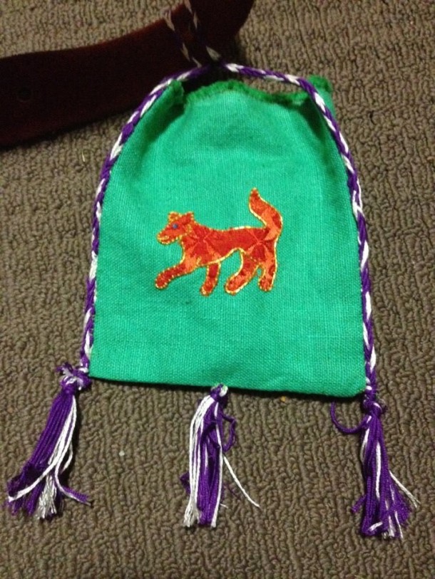 The favour I made for my consort Macca. A fox (my primary charge) appliqued and outlined in gold. The pouch is linen. I also made the cords and tassels myself.