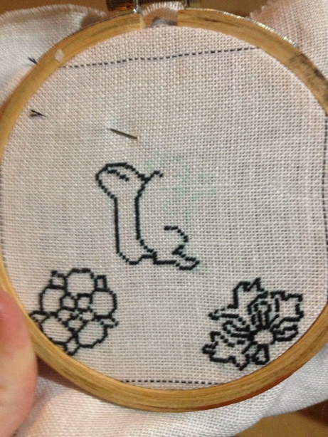 Outline of rose, honeysuckle and incomplete squirrel outline in black silk tent stitch.