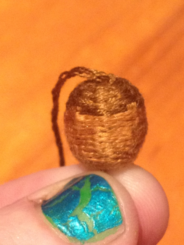 1/5 thread wrapped bead acorns. The light brown silk is the reverse spine stitch and the dark brown silk is basketweave. The core is a wooden bead.
