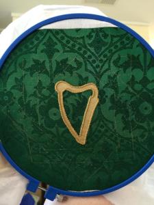The green fabric with gold harp body appliqued on. Here, I've already outlined the body of the harp in gold twist.