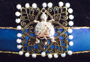 Figure 16: Close up of the front-centre filigree square, tortoise and pearls couched to the hat band.
