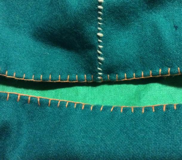 Close up of the buttonhole stitching along the bottom (in orange wool) and the whip stitch along the seams (white wool). Photo and work by Ceara Shionnach, April 2015.