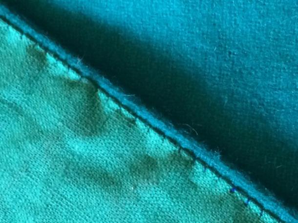 A close up of the stab-stitching that was done by hand to line the woolen shawl with linen. Photo and work by Ceara Shionnach, April 2015.