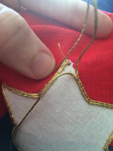 Put one strand of the gold cord through the loop and pull it through the hole made by the awl.