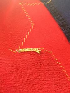 Couch about 2cm of the tail of gold cords on the back of the fabric to secure it. You should couch along one of the couching lines of your shape to ensure no sewing thread will be visible on the surface of your embroidery.