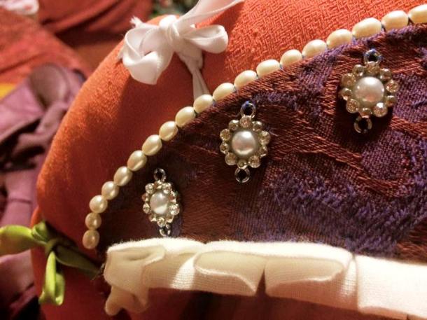 A close up of one edge of the buckram 'tiara' with the pearls, broken up jewellery flowers and pleating evident. Photo by THL Ceara Shionnach, 2015.
